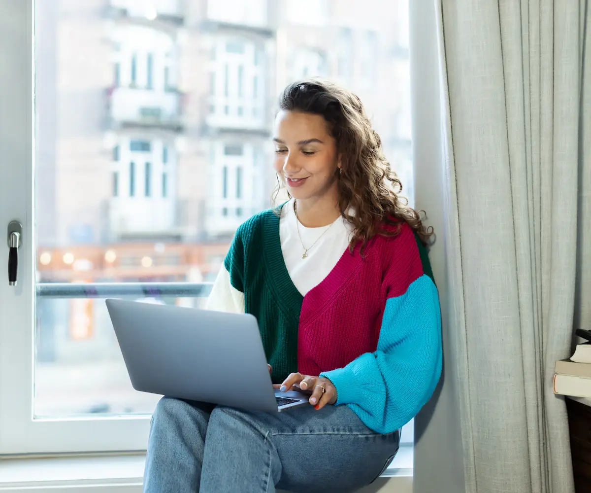 A freelancer working on a laptop from a sunny apartment
